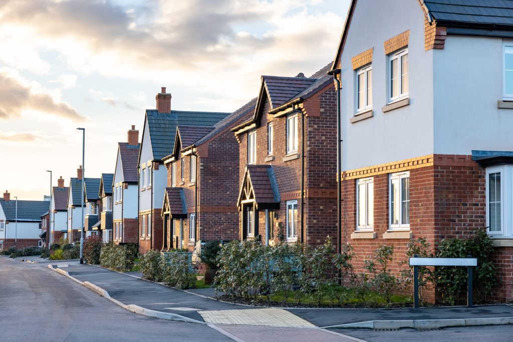 Houses in England with typical red bricks at sunset - Main street in a new estate with typical British houses on the side - Real estate and buildings concepts in UK